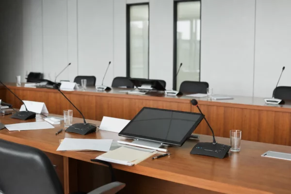 Salle de colloque institutionnelle à l’hôtel de Lassay, avec table en bois, micros, verres d’eau et rangées de chaises.