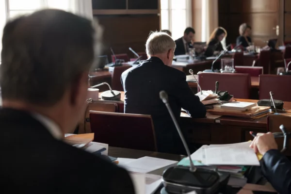Salle de commission à l’Assemblée nationale avec pupitres, micros et dossiers avant l’examen du budget