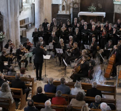 Pupitres, chaises et instruments à cordes installés dans une église pour un concert réunissant musiciens et choristes.