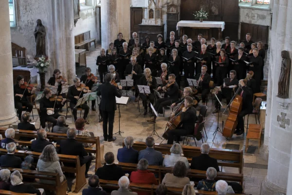 Pupitres, chaises et instruments à cordes installés dans une église pour un concert réunissant musiciens et choristes.