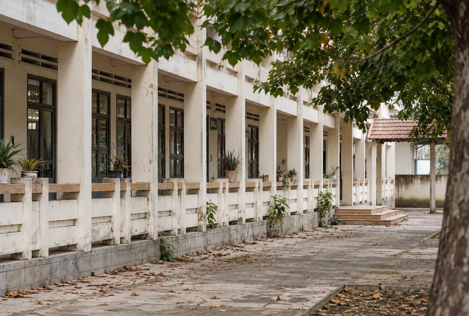 Cour d’école aux dalles usées et aux fenêtres répétées d’une façade, dans un état ordinaire avant rénovation.