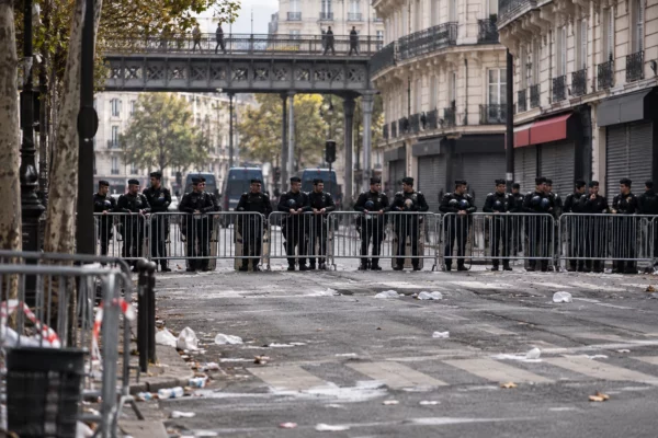 Policiers et gendarmes derrière des barrières métalliques dans une rue parisienne, alors que la chaussée se dégage.