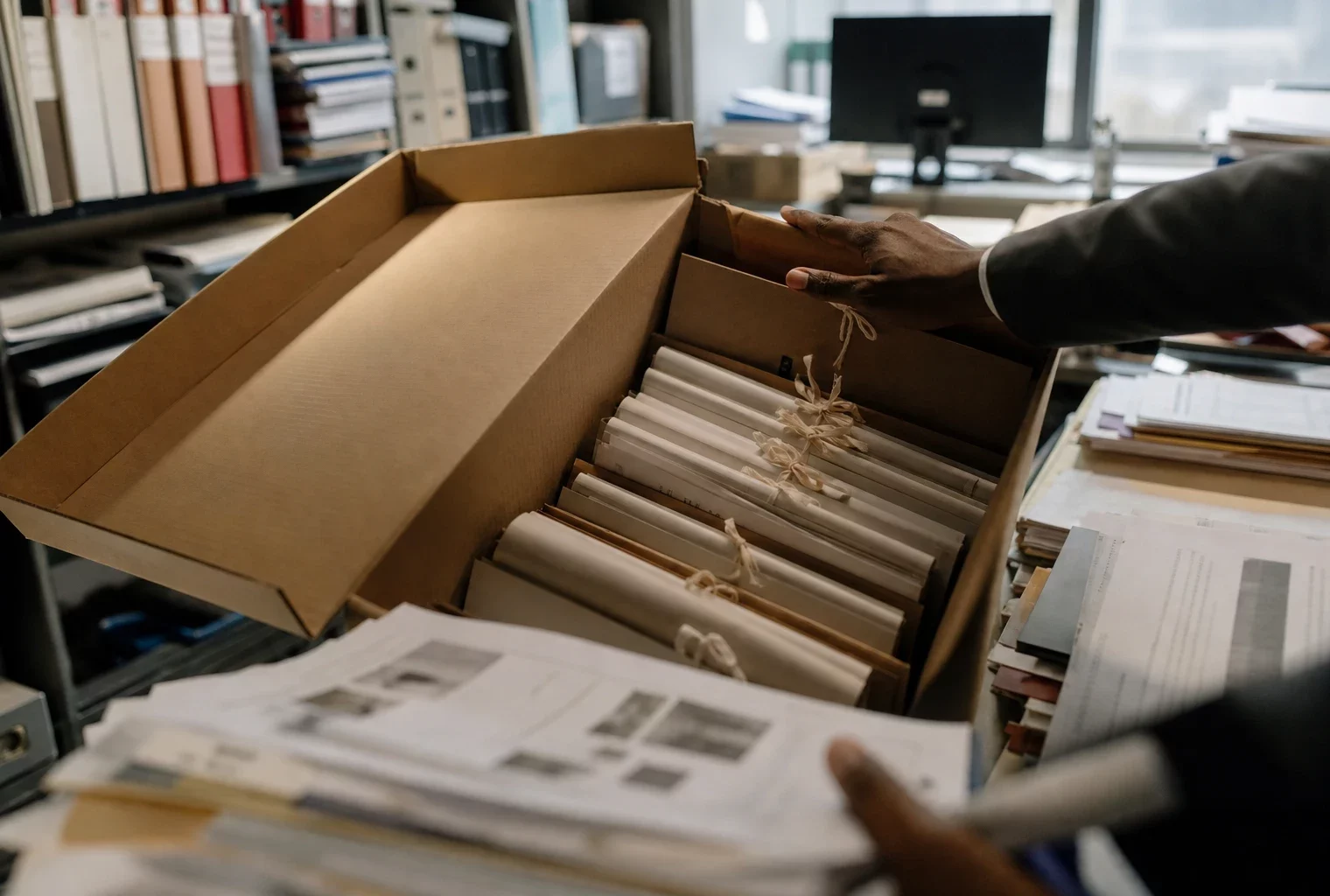 Dossier de pièces imprimées dans un cabinet d’instruction, avec mains au travail, étagères juridiques et lumière froide.