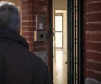 Entrée d’immeuble sécurisée en France, porte métallique, interphone et boîtier de contrôle dans un hall neutre.
