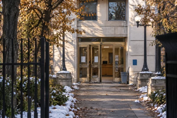 Entrée vitrée d’une mairie aux menuiseries endommagées, avec un hall d’accueil visible derrière la porte et une façade en pierre.