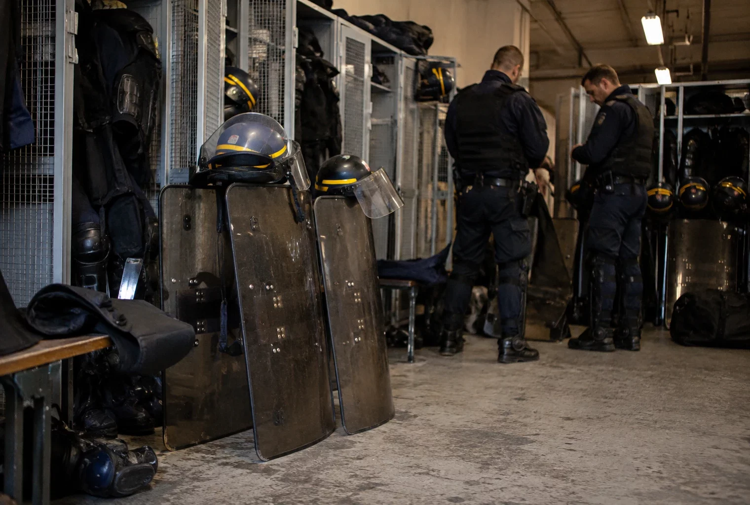 Boucliers, casques et protections individuelles rangés dans un espace de préparation d’une unité de maintien de l’ordre.
