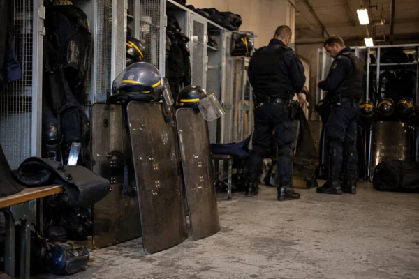 Boucliers, casques et protections individuelles rangés dans un espace de préparation d’une unité de maintien de l’ordre.