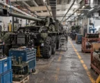 Un châssis de canon automoteur Caesar en cours d’assemblage dans un atelier industriel encombré de machines et d’outils.