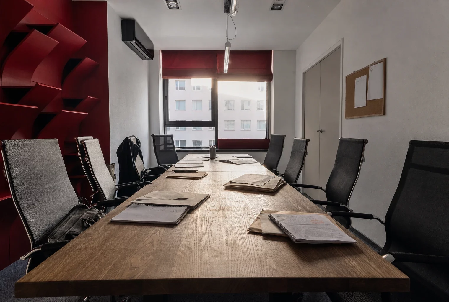 Salle de réunion parisienne sobre avec grande table en bois, chaises vides et dossiers, dans un local de jeunesse politique.
