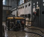 Un générateur électrique portable relié à un tableau de distribution dans un local technique aux équipements usés.