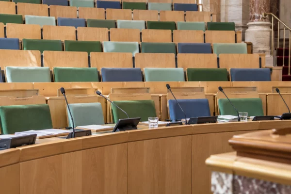 Pupitres équipés de microphones et sièges aux couleurs variées dans l’hémicycle de l’Assemblée nationale.