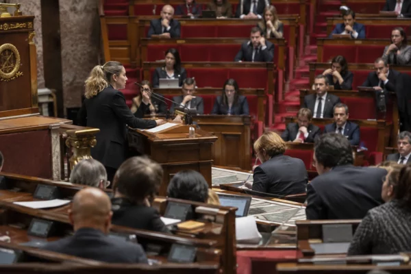 Pupitres équipés de microphones et de consoles de vote dans un hémicycle parlementaire aux rangées de sièges visibles.