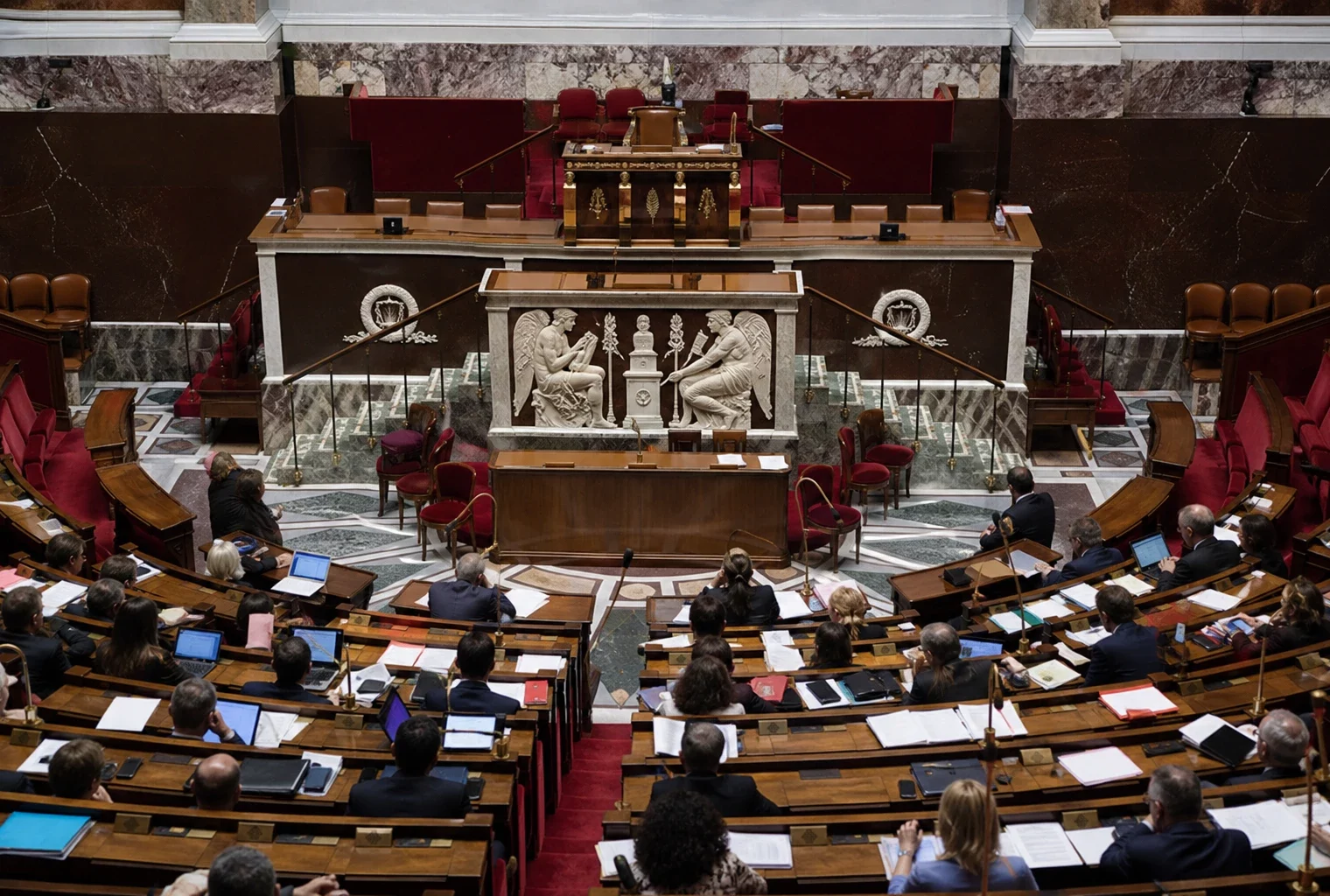Hémicycle de l’Assemblée nationale avec pupitres et micros, symbole du débat sur le budget 2027.