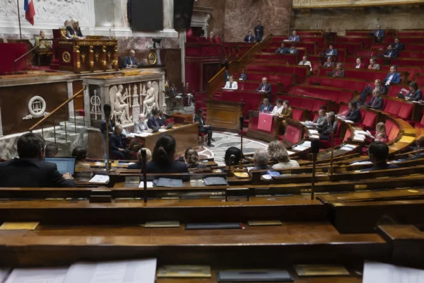 Rangées de pupitres équipés de microphones et de boîtiers de vote dans un hémicycle parlementaire.