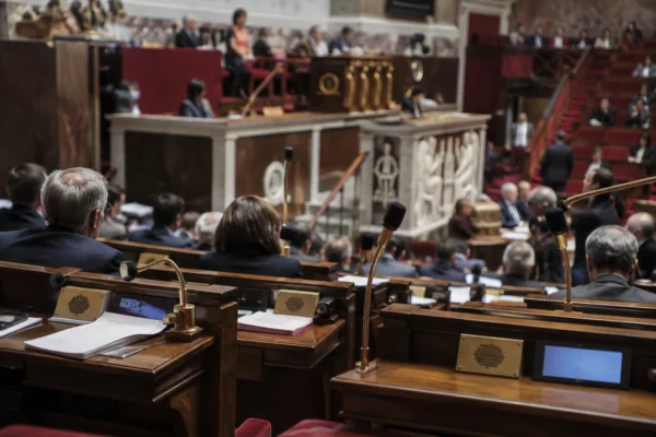 Pupitres équipés de microphones et de boîtiers de vote dans un hémicycle parlementaire aux rangées de sièges incurvées.
