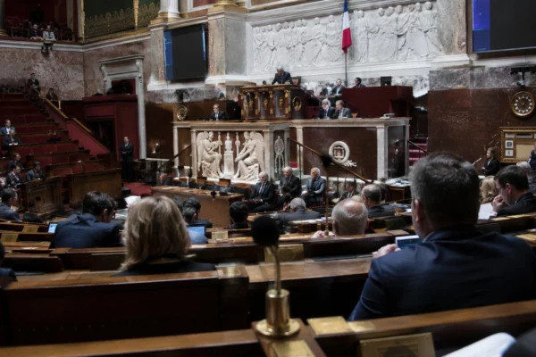 Pupitres équipés de microphones alignés dans un hémicycle parlementaire, avec des rangées de sièges en gradins.