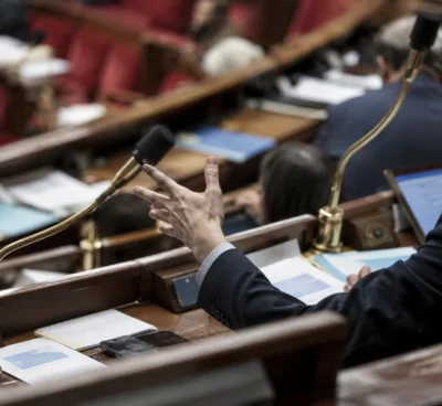 Pupitres équipés de microphones et documents de séance dans un hémicycle aux rangées incurvées de sièges.