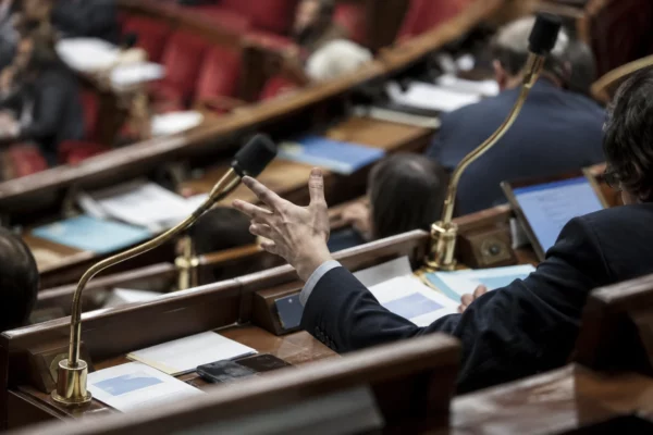 Pupitres équipés de microphones et documents de séance dans un hémicycle aux rangées incurvées de sièges.