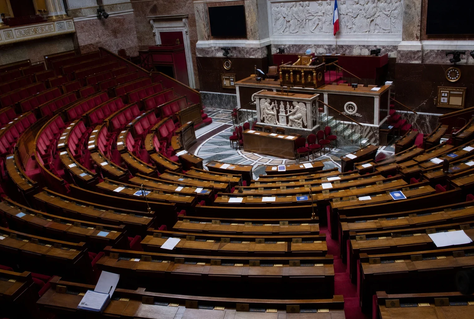 L’hémicycle de l’Assemblée nationale vide, avec ses rangées de sièges et de pupitres.