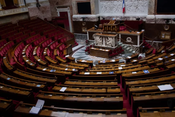 L’hémicycle de l’Assemblée nationale vide, avec ses rangées de sièges et de pupitres.