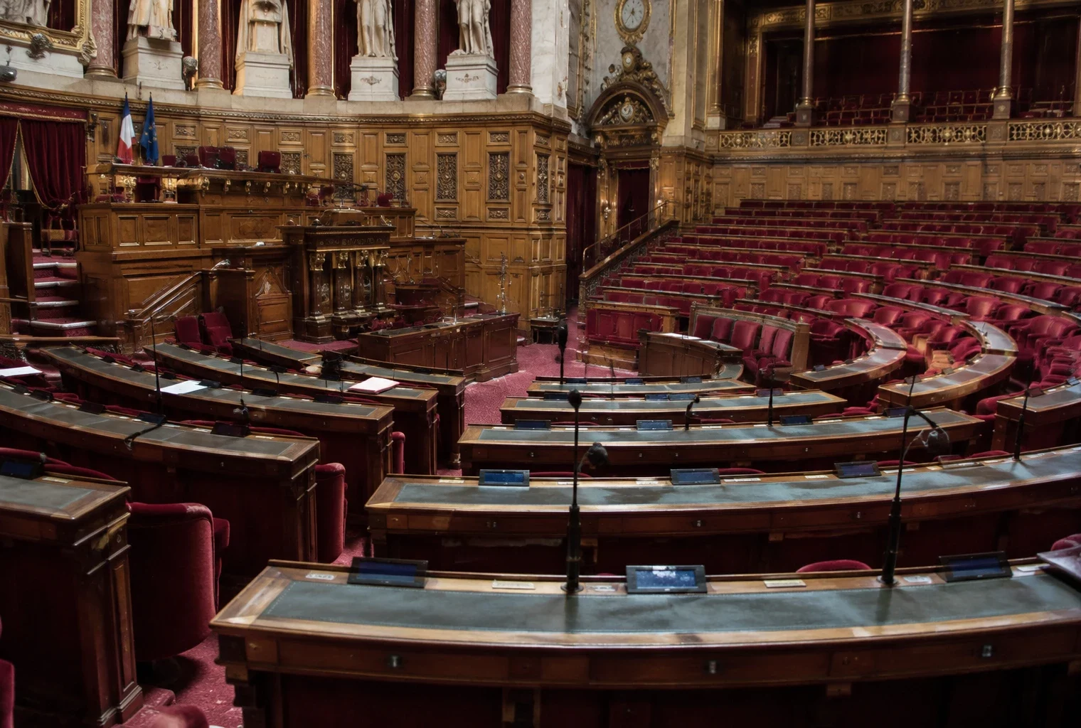 Pupitres équipés de microphones et de boîtiers de vote disposés en arc de cercle dans un hémicycle parlementaire.