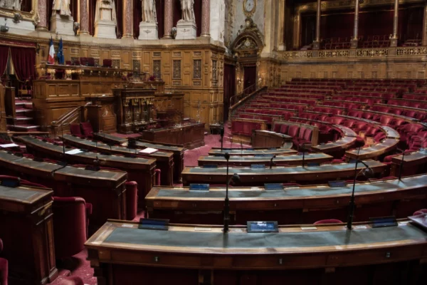 Pupitres équipés de microphones et de boîtiers de vote disposés en arc de cercle dans un hémicycle parlementaire.