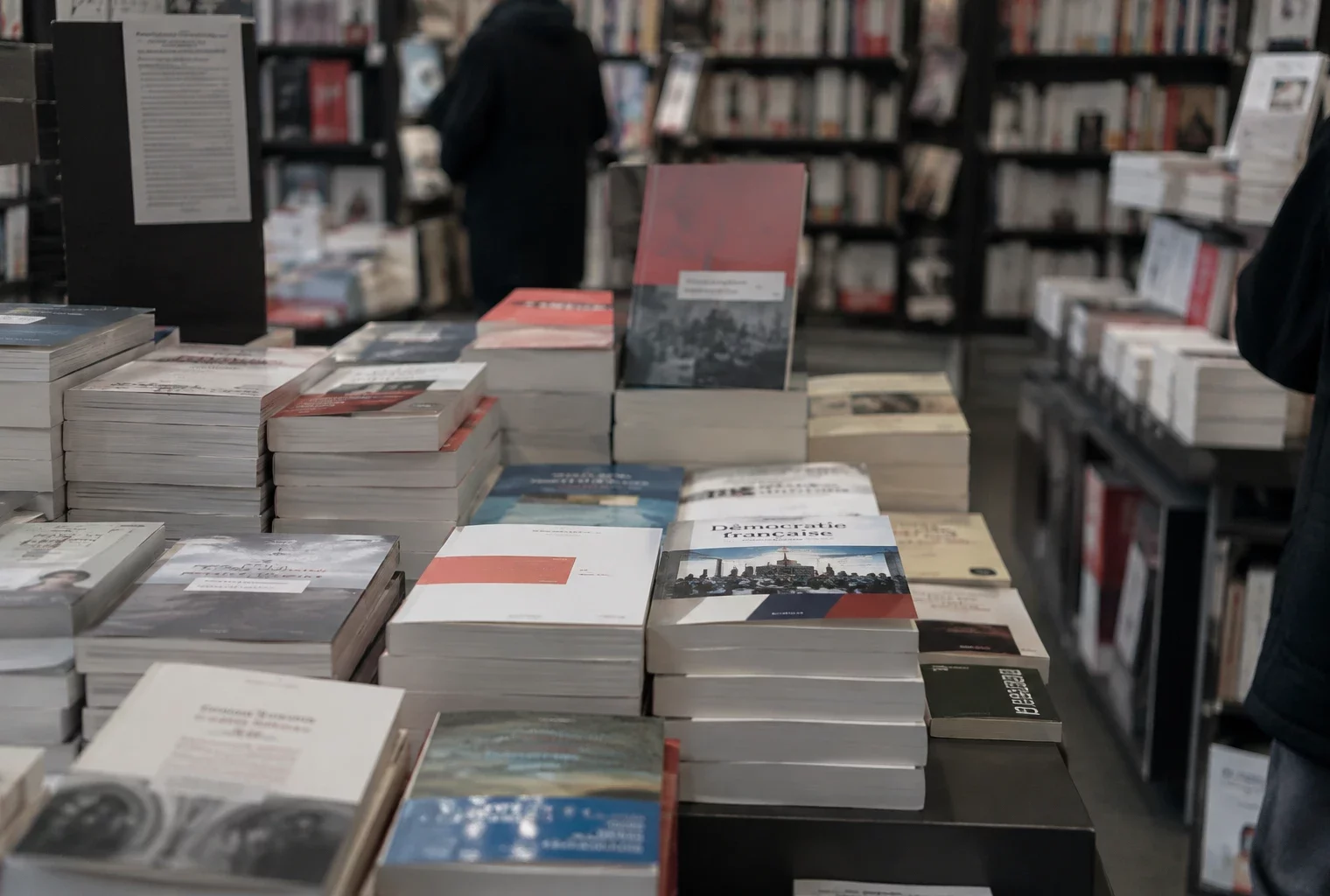 Un livre politique posé parmi d’autres ouvrages sur une étagère de librairie, avec des rayons garnis en arrière-plan.