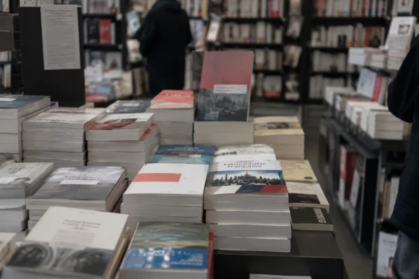 Un livre politique posé parmi d’autres ouvrages sur une étagère de librairie, avec des rayons garnis en arrière-plan.