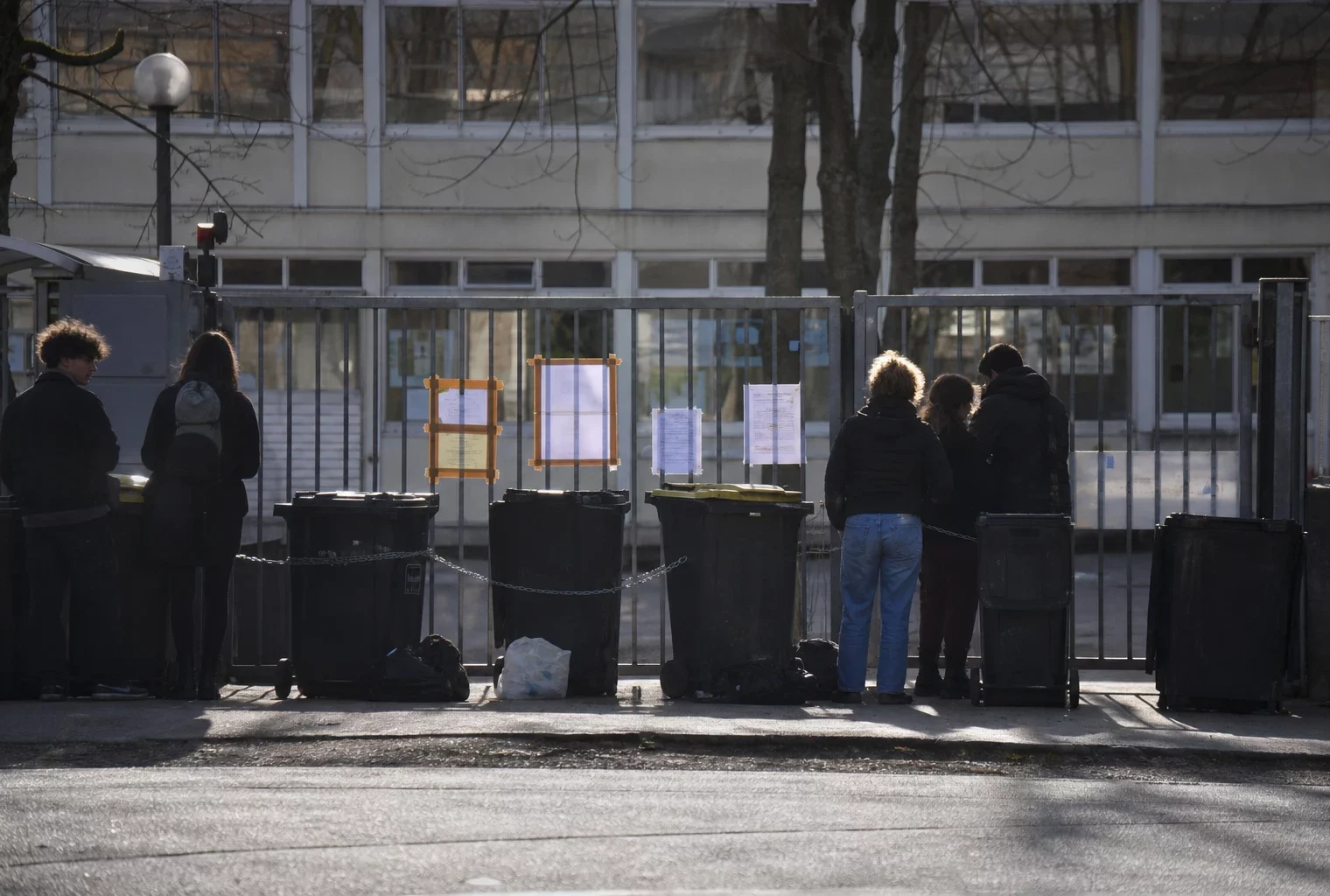 Entrée de lycée bloquée par des barrières et des objets posés devant le portail.
