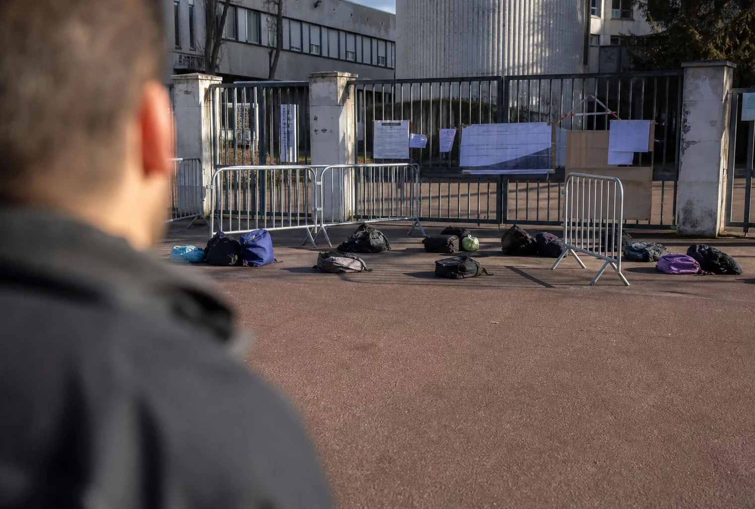 Entrée d’un lycée bloqué avec grilles fermées et barrières devant l’établissement