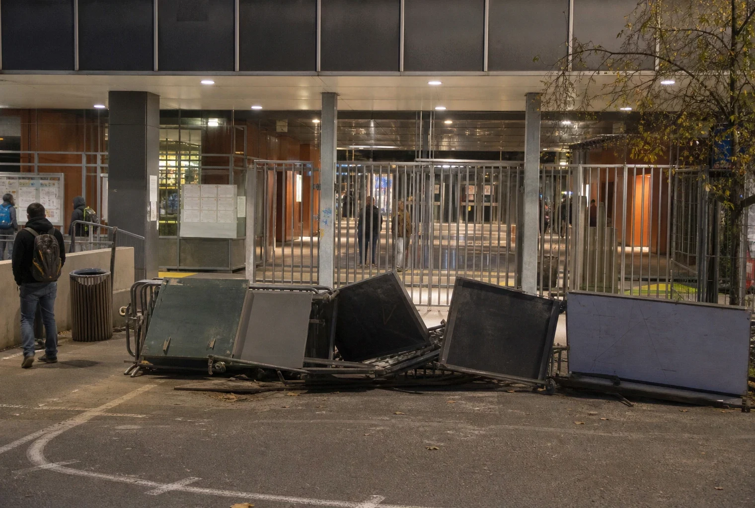 Entrée de lycée fermée par des barricades, avec le portail et la façade de l’établissement en arrière-plan.