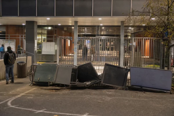 Entrée de lycée fermée par des barricades, avec le portail et la façade de l’établissement en arrière-plan.
