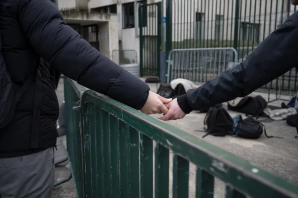 Des élèves devant l’entrée bloquée d’un lycée, avec des barrières et un portail fermé.