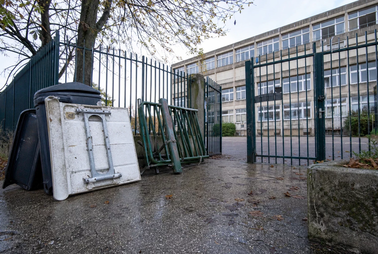 Entrée d’un lycée public bloquée, avec grilles fermées et obstacles devant le portail.