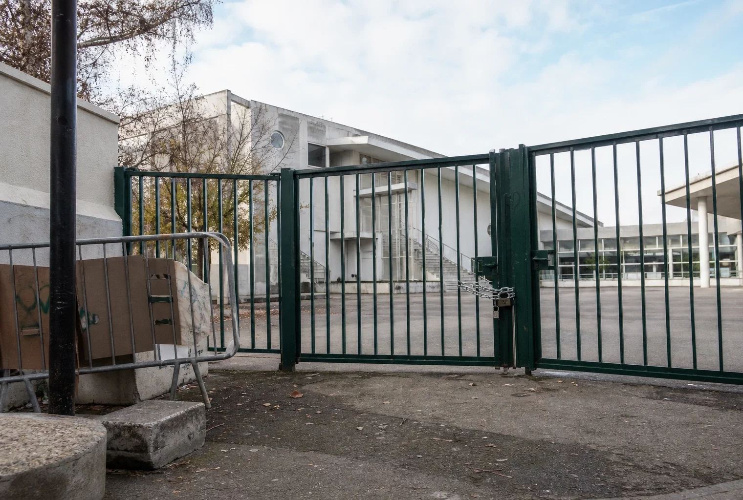 Entrée d’un lycée fermé par un blocage, avec grille close et barrières devant le bâtiment.