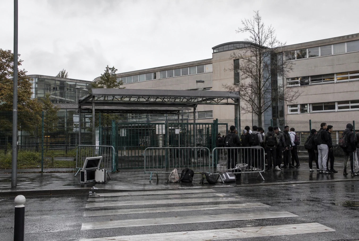 Devant le lycée Paul-Éluard à Saint-Denis, l’entrée bloquée avec des élèves rassemblés sur le trottoir.