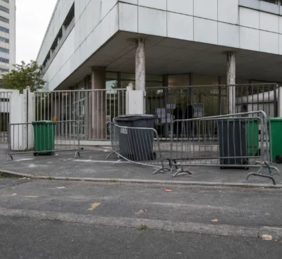 Entrée d’un lycée bloquée à Saint-Denis, avec barrières et poubelles devant les grilles.