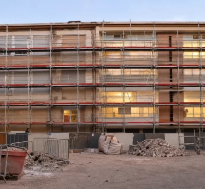 Façade d’un lycée public en rénovation, sous échafaudages, avec barrières de chantier et zones de travaux visibles.