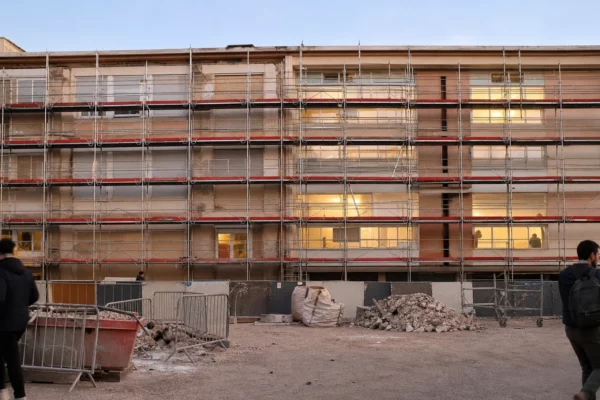 Façade d’un lycée public en rénovation, sous échafaudages, avec barrières de chantier et zones de travaux visibles.
