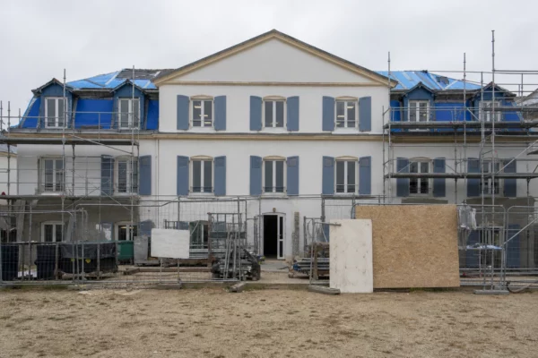 Façade d’un lycée public en travaux, avec échafaudages, barrières de chantier et cour d’établissement en arrière-plan.