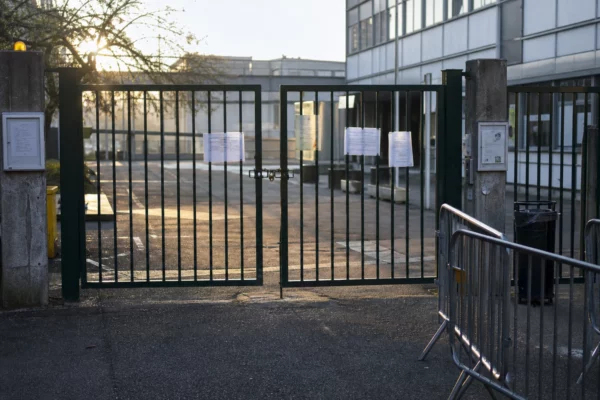 Grille fermée d’un lycée, avec barrières et affichages, symbole de cours suspendus pendant la mobilisation.