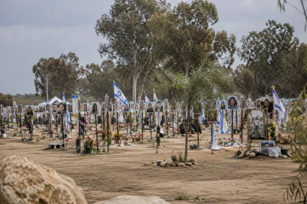 Hommages déposés sur un mémorial en plein air, au milieu d’un terrain ouvert, sans visiteurs visibles.