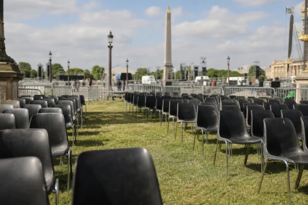 Rangées de chaises noires et barrières de sécurité sur la place de la Concorde, avec l’obélisque en arrière-plan.