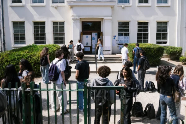 Attroupement d’élèves devant le portail d’un lycée public français, avec sacs à dos et façade en arrière-plan.