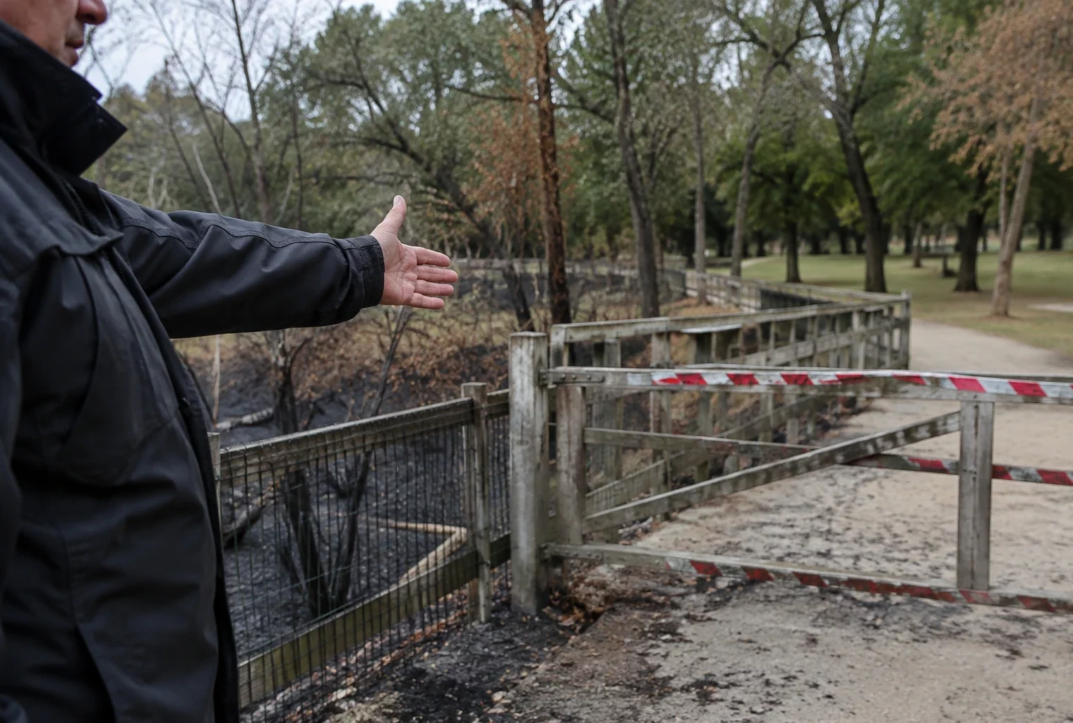 Passerelle fermée dans un parc public, avec une partie de l’espace canin inaccessible et de la végétation brûlée aux abords.