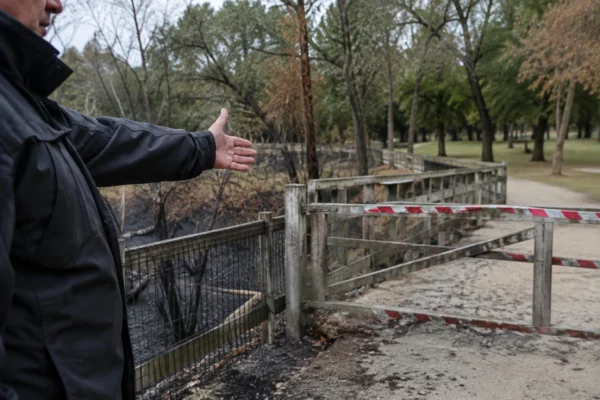 Passerelle fermée dans un parc public, avec une partie de l’espace canin inaccessible et de la végétation brûlée aux abords.