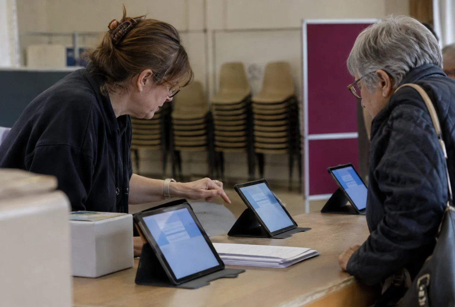 Des tablettes sont disposées sur un comptoir dans une salle polyvalente aménagée pour accompagner le vote en ligne.