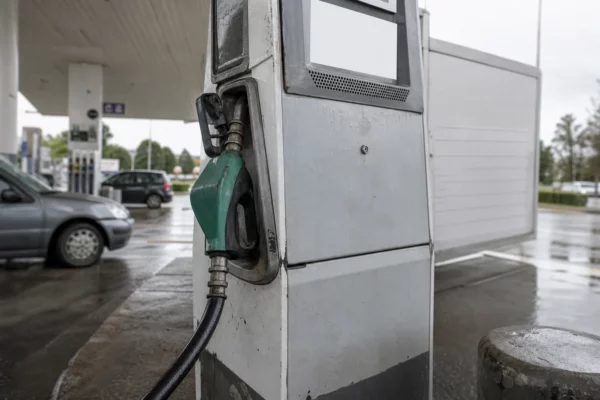 Pompe à carburant humide en bord de route, gros plan sur le pistolet et le flexible, station-service sous la pluie.