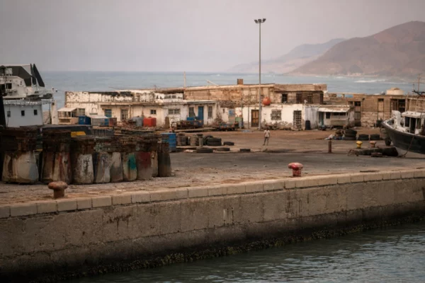 Quais en béton du port de Mokha, bollards usés, embarcations de travail et bâtiments bas face à la mer Rouge.