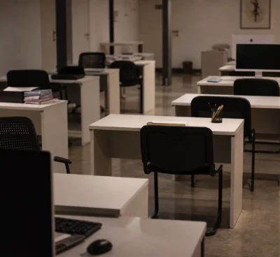 Bureau d’administration publique presque vide, écrans éteints et postes de travail désertés sous lumière chaude du soir.